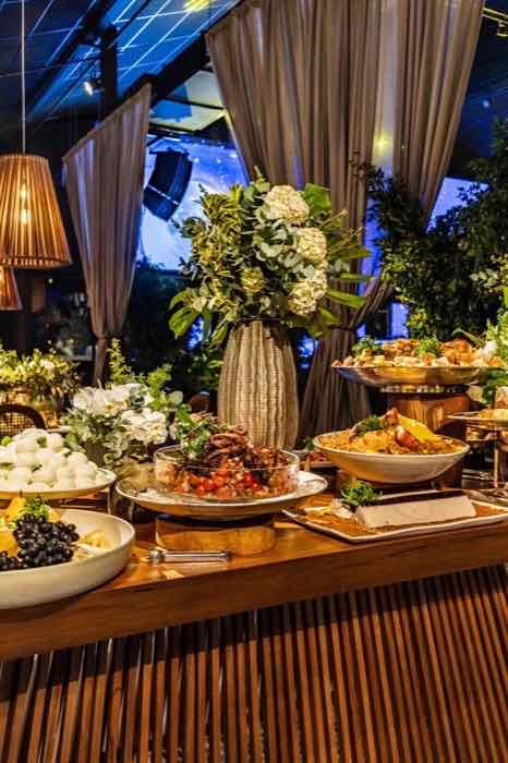 Mesa de buffet elegante com flores, louças e pratos preparados